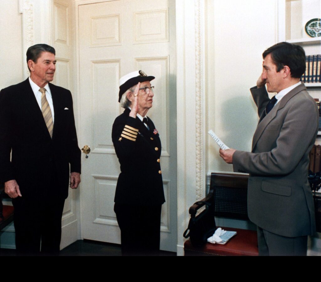 Secretary of the Navy John Lehman, right, promotes Capt. Grace Hopper to the rank of commodore in a ceremony at the White House. President Ronald Reagan is on the left.