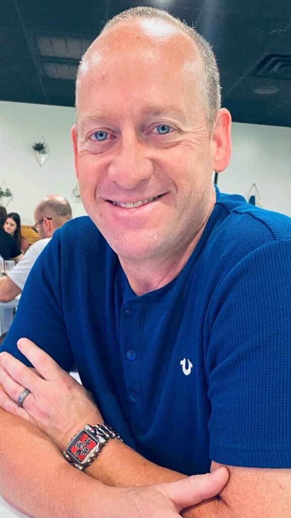 A man in a blue shirt with a red wristwatch