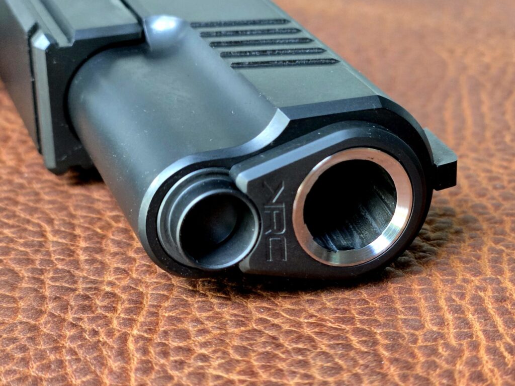 The muzzle and dust cover of the 1911 pistol on a leather backdrop