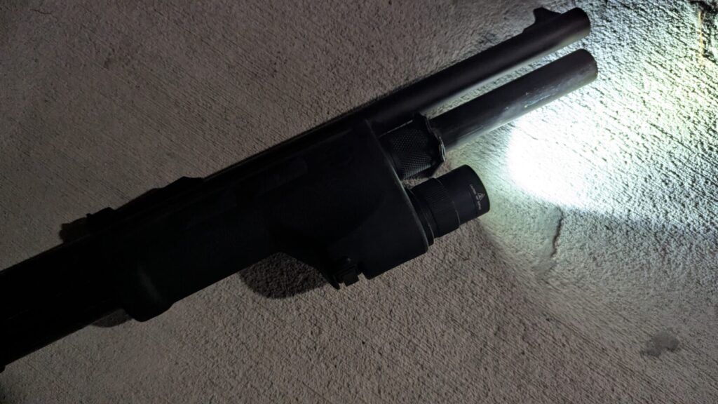 The Surefire DSF mounted to a shotgun with the light on, beam on concrete at night