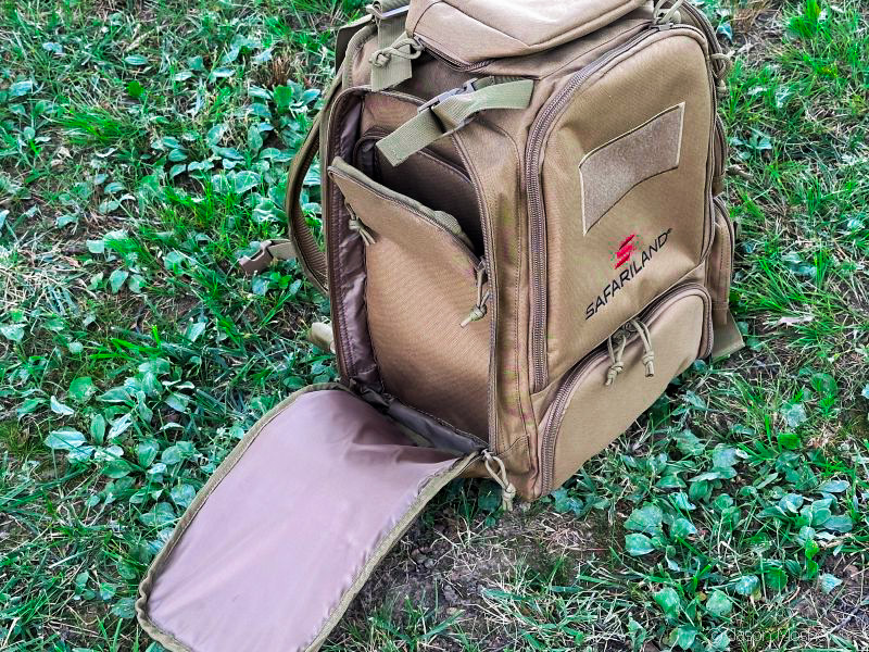 A brown backpack sitting on the ground with the left-side compartment unzipped and open.