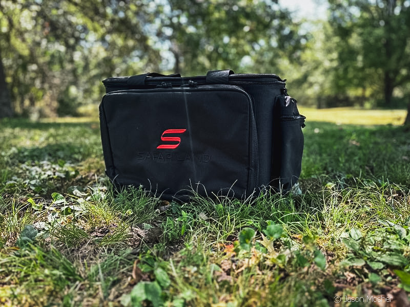 A black duffle style bag on the ground with green grass around it.