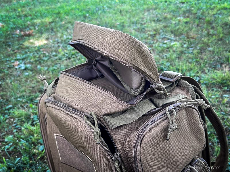 A brown backpack sitting on the ground. The top compartment is unzipped and open.