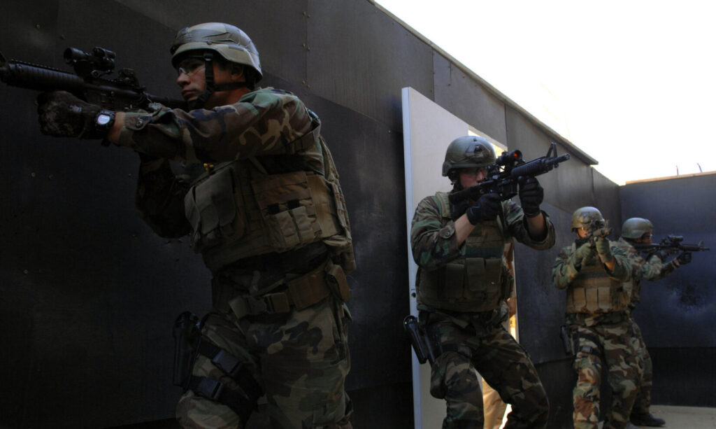 Four Navy SEAL trainees practice a room breaching exercise as part of SEAL qualification training instruction. Students spend two weeks learning the basic methods for entering a room and securing it from possible threats. (U.S. Navy photo. Public Domain)