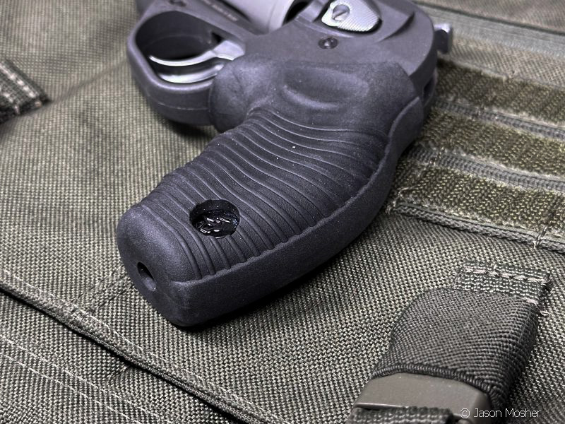 A close up of the rubber grip on the 605 Poly revolver, laying on a green canvas bag. 