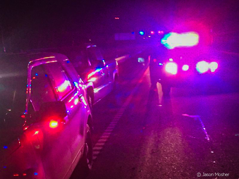 Police car on a traffic stop at night with red and blue lights on. 