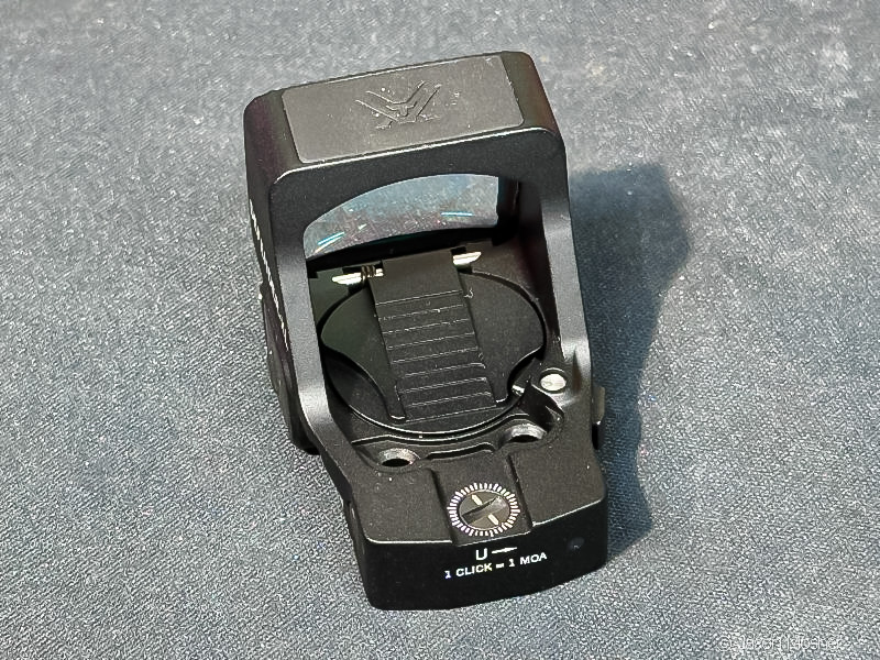 The Vortex Defender XL handgun optic on a charcoal surface with a view of the battery compartment in the back.