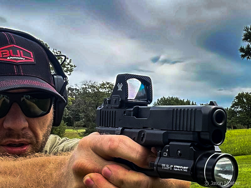 A person with sunglasses and a black hat shooting a Glock 47 with the Vortex Defender optic attached to it.