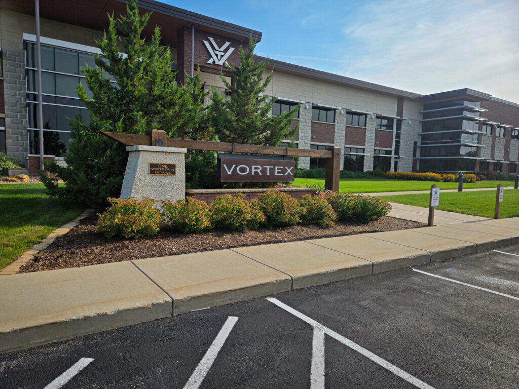 Photo of the Vortex facility with a wooden sign and colorful flowerbed.