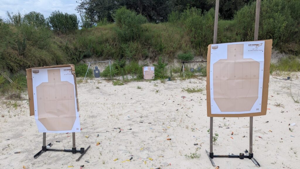 two close paper targets up close, one paper target between two steel targets at a further distance, in front of the berm at an outdoor gun range