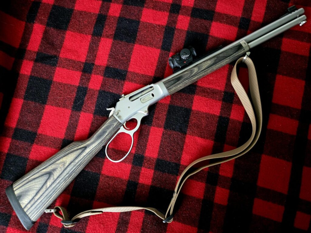 Stainless steel lever gun on top of a red plaid backdrop.