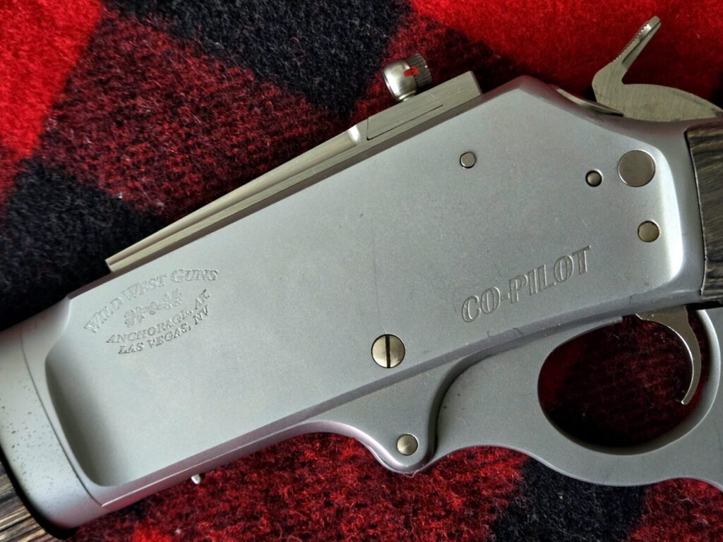 Stainless steel lever gun receiver engraving on a red plaid backdrop.