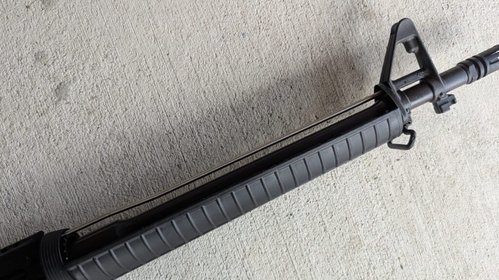 Close-up of the front sight and handguard of a black dissipator rifle, showing the barrel underneath.