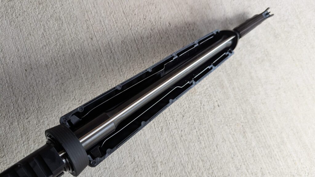 A close-up of the front part of a dissipator rifle, showing the handguard and the barrel inside, on a concrete background.