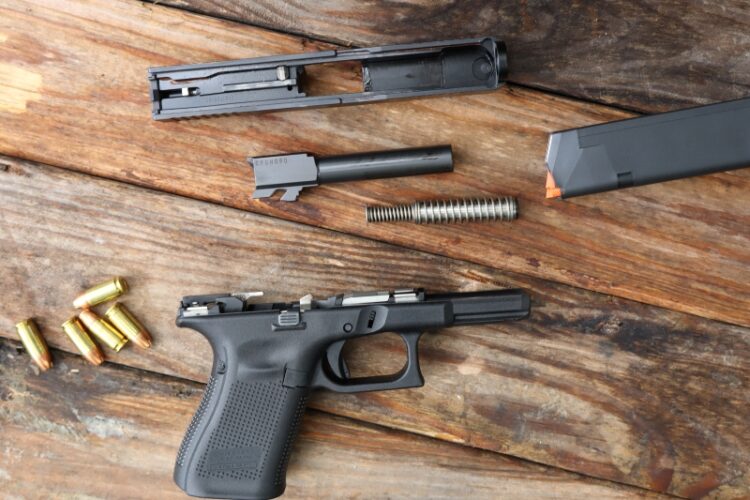 disassembled Glock 19 and 9mm ammo on wooden surface
