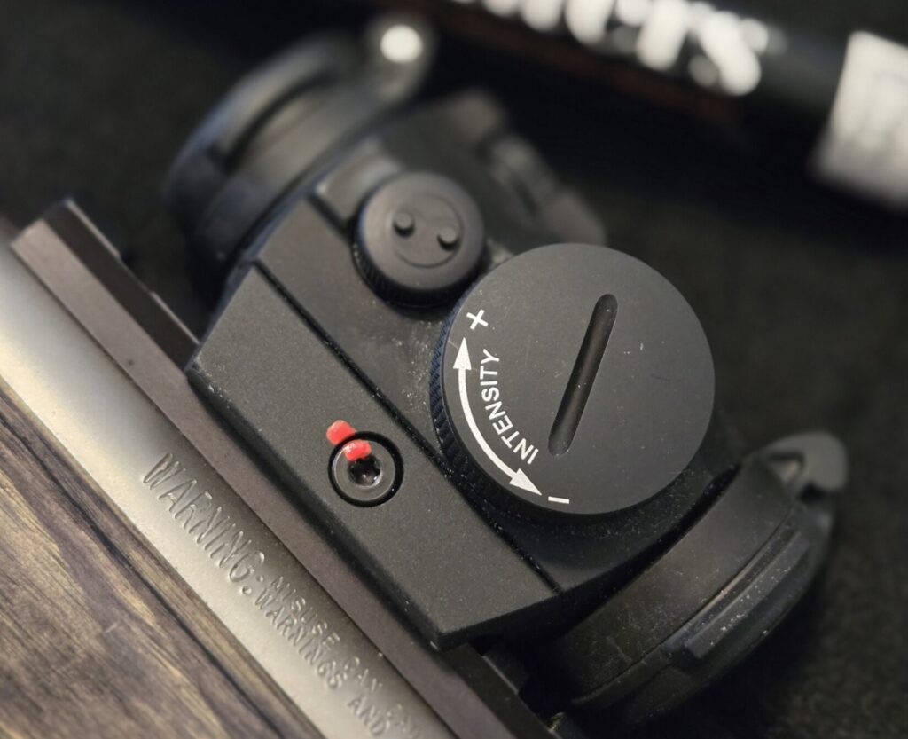 An Aimpoint H2 optic on top of a stainless steel barrel.
