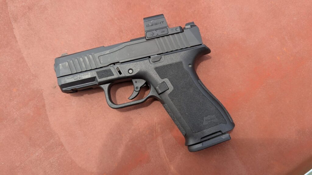 A PSA pistol with an optic, shown on a textured red surface.