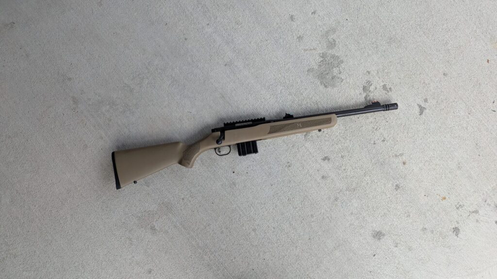 A Mossberg MVP Patrol rifle with a black magazine lying on a concrete surface.