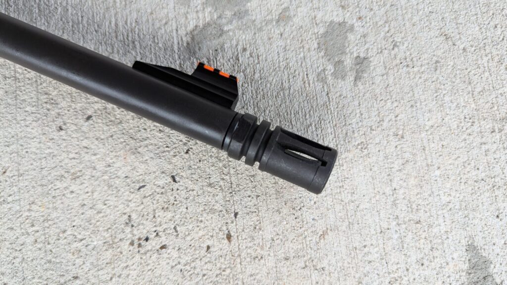 A close-up of the Mossberg MVP Patrol rifle's muzzle device on a concrete background.