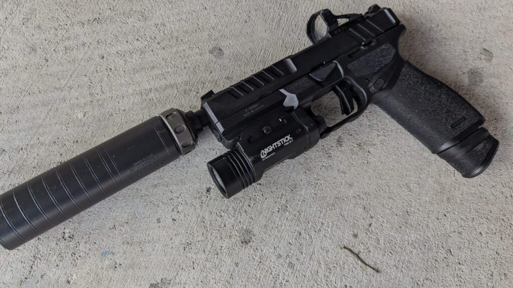 A close-up view of a Springfield Echelon pistol with a Nightstick TWM-30-T weapon light and a suppressor attached to the barrel.