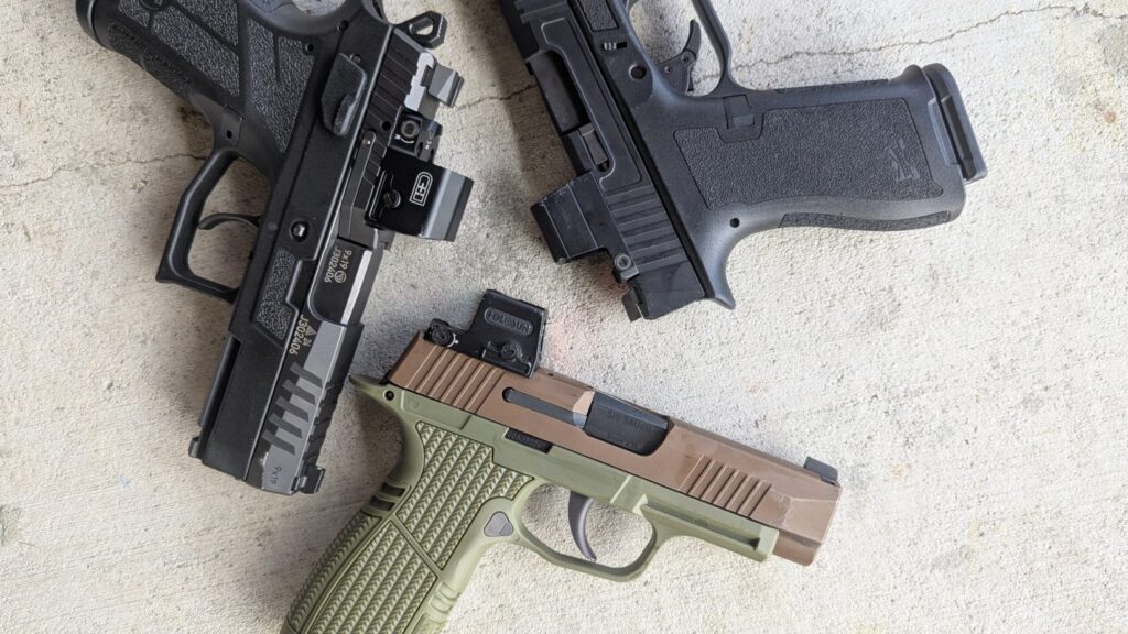 Three handguns on a concrete surface: a black one with an Osight S, a two-toned tan and green one with a Holosun EPS Carry, and a black one with an EDC Enclosed