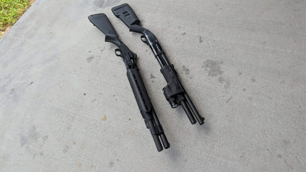 Two black shotguns, one with a Surefire DSF forend and one with a Holosun red dot sight, lying on a concrete surface.