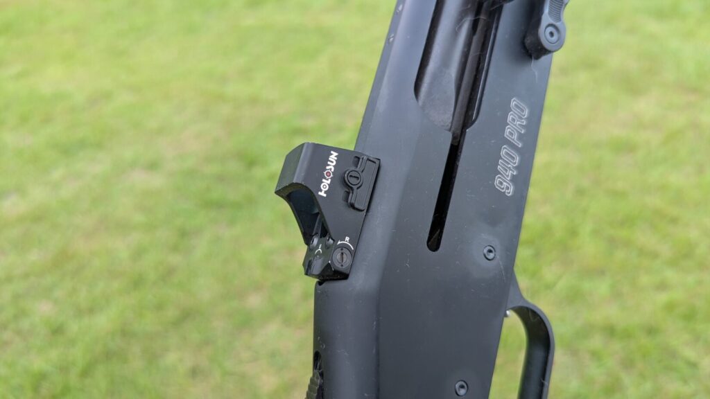 A black Mossberg 940 Pro Tactical shotgun on a Holosun red dot sight
