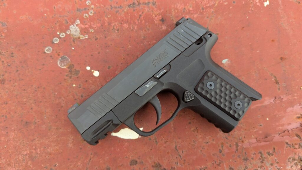 Black P365 with S365 grip on red surface.