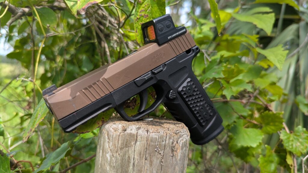 P365 with S365 grip and optic on a post, greenery behind.