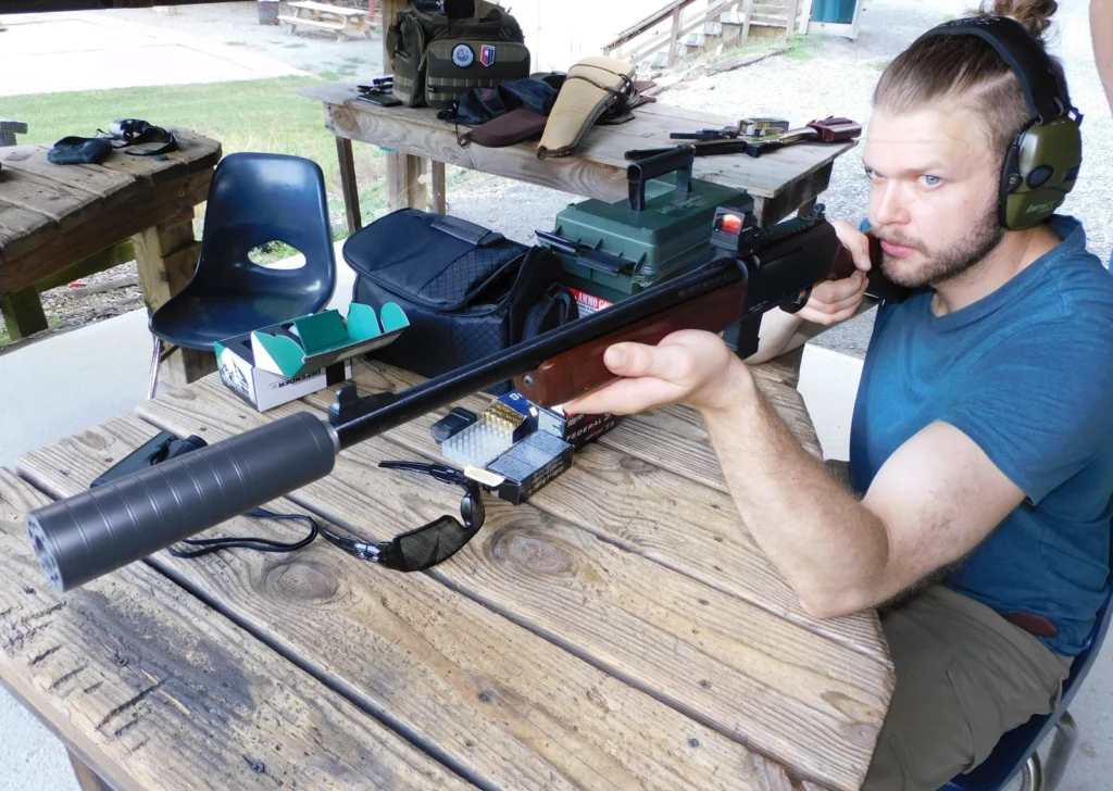 Man firing a Henry Homesteader carbine with a SilencerCo Spectre 9 suppressor