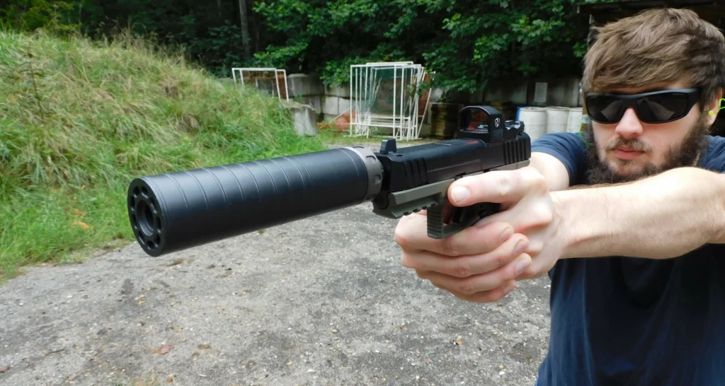 Man firing an IWI Masada pistol with a SilencerCo Spectre 9 suppressor