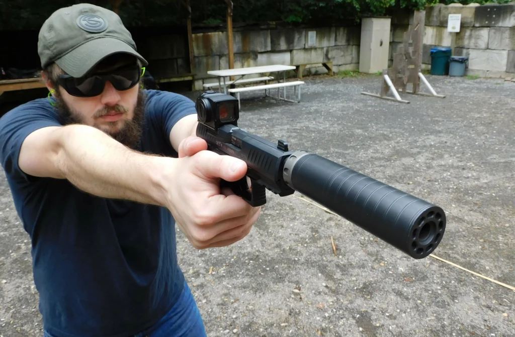 Man firing a Walther PPQ pistol with a SilencerCo Spectre 9 suppressor