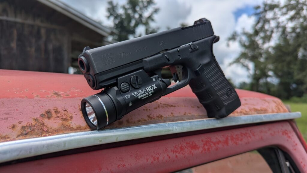 The Glock 17 with the Streamlight TLR-1 HL-X is on a rusty red surface.