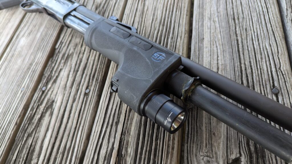 Close-up of the Surefire DSF weaponlight's forend on a shotgun, resting on a wooden surface.