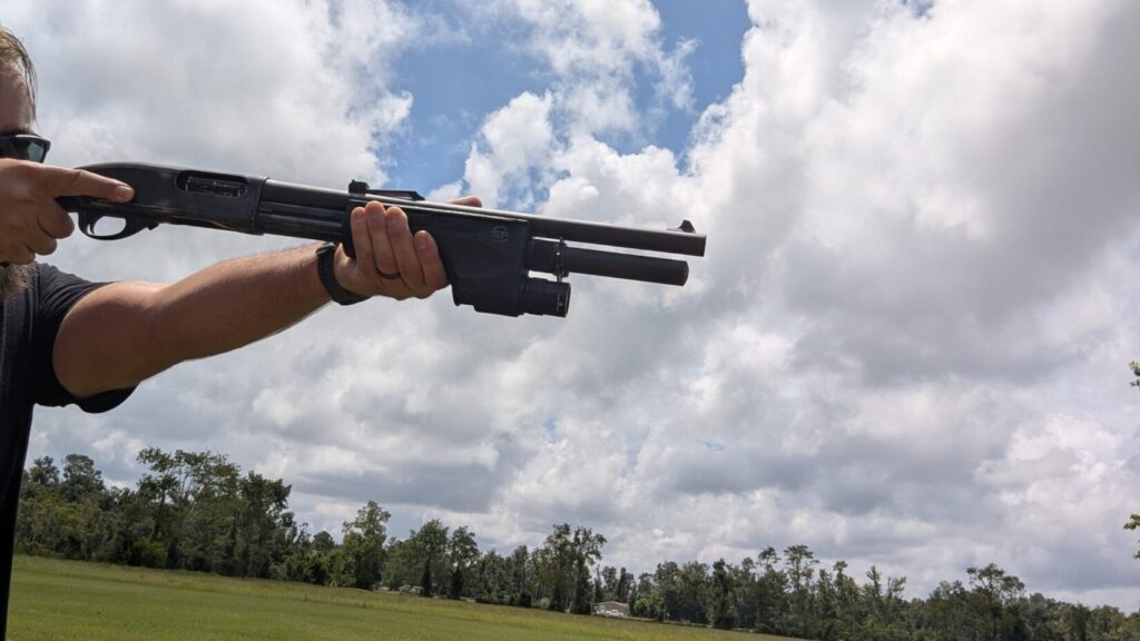 Person holding a shotgun with a Surefire DSF weaponlight, aiming .