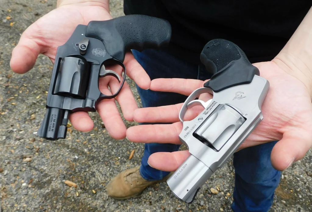 Man holding two snub nose revolvers on his palms