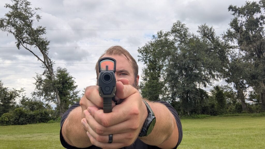 A person holds and aims the Arex Delta Gen 2 pistol with the Swampfox Justice 2 optic