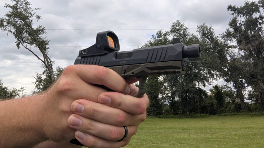 A hand holds an Arex Delta Gen 2 pistol with a Swampfox Justice 2 optic.