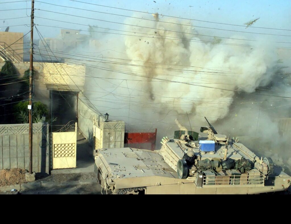 A U.S. Marine Corps M1A1 Abrams Main Battle Tank (MBT), 2nd Tank Battalion (BN), fires its main gun into a building to provide suppressive counterfire against terrorists who fired on other Marines during a firefight in Fallujah, Al Anbar Province, Iraq. (US. Marine Corps photo by Lance Corporal James J. Vooris. Public Domain)