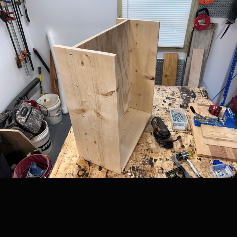 Two upright panels of raw wood with a square piece of plywood attached to the center. 