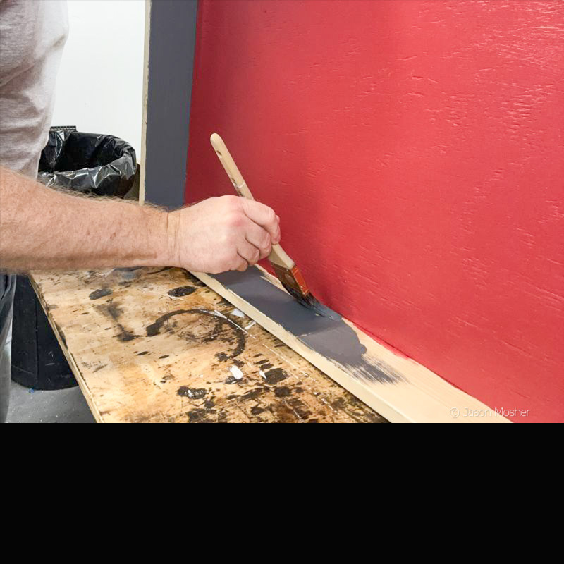 A person holding a paint brush and painting the side of the holster cady. 