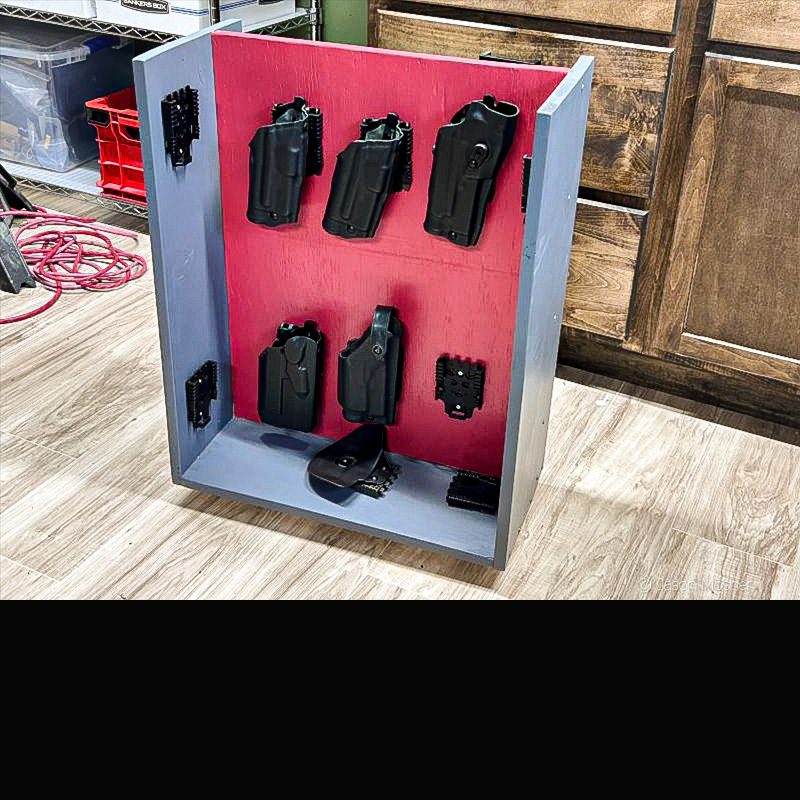 A holster caddy with several holsters mounted over the red background. 