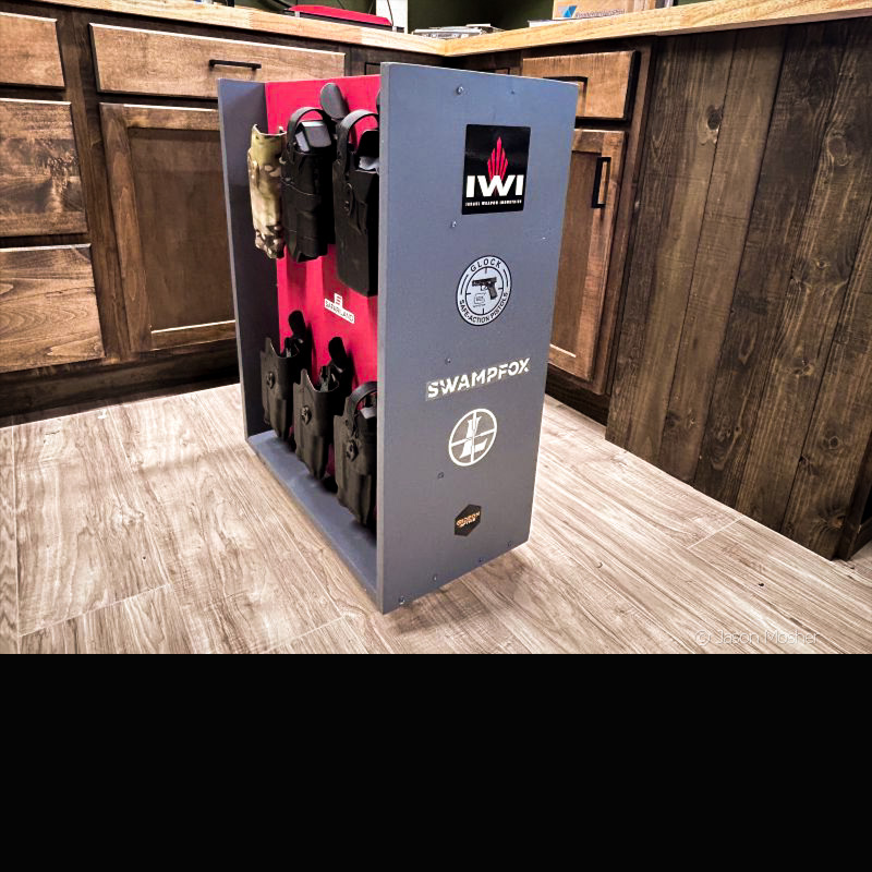 A grey holster caddy on the floor with a red center and stickers on the end of the caddy. 