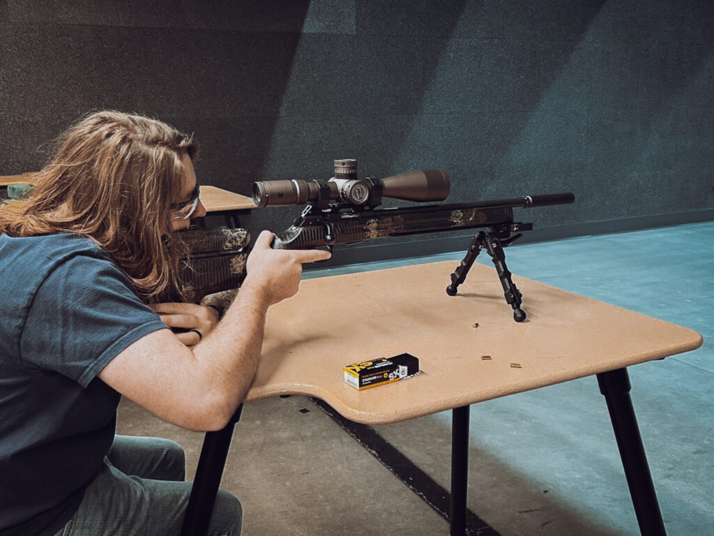 man shooting long gun with a scope in an indoor range