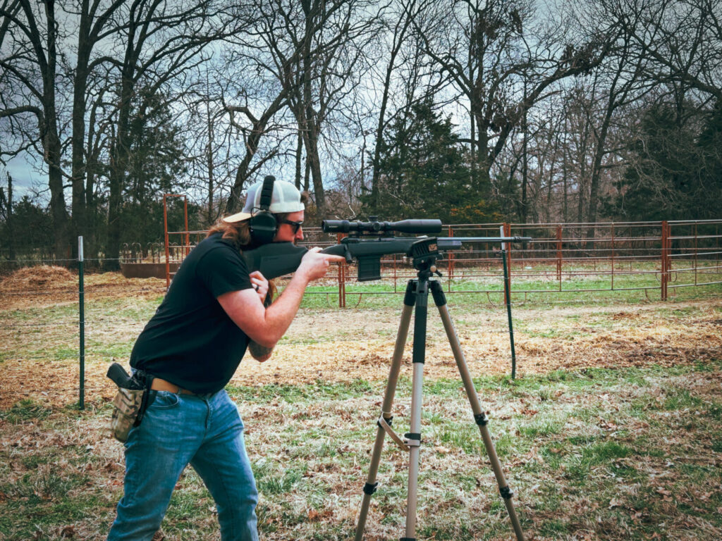 man shooting a rifle from a tripod