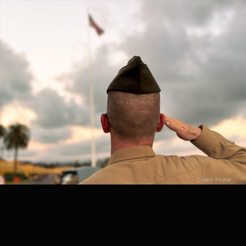 A US Marine looking up at the US flag as he solutes. 
