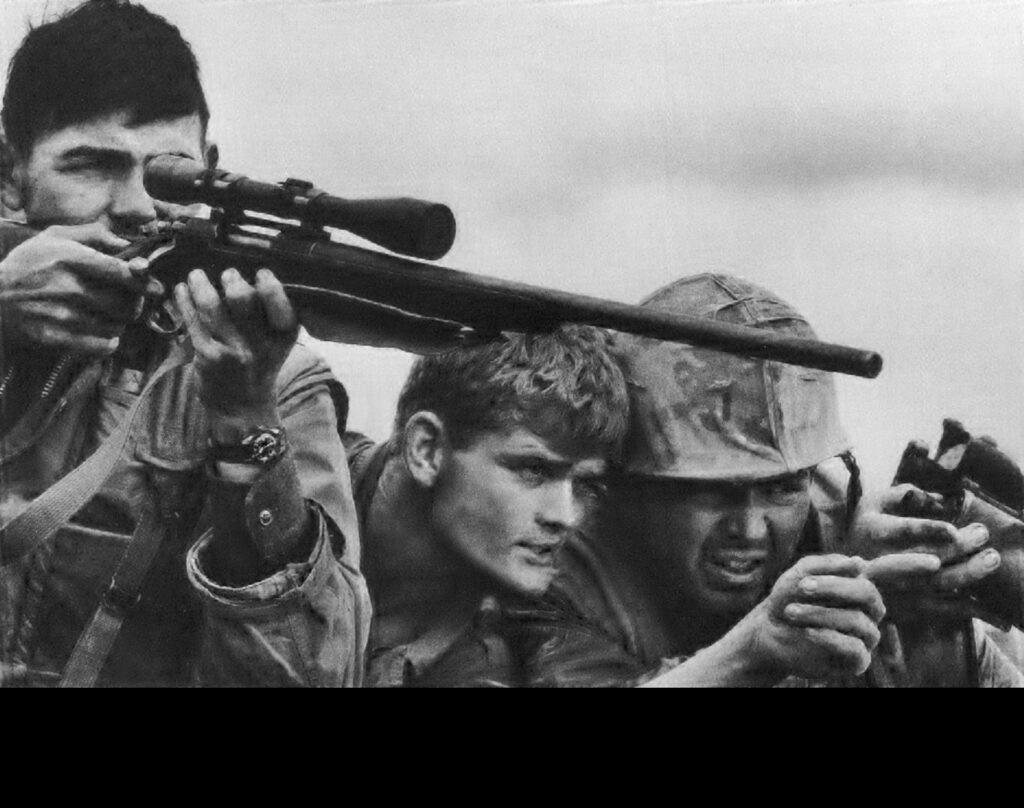 A U.S. Marine Corps sniper team searches for targets in the Khe Sanh Valley. Original photo by David Douglas Duncan. Donated for use by his estate to the USMC. (Photo by David Douglas Duncan. Public Domain)
