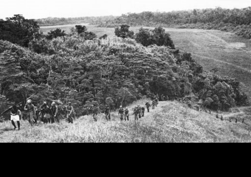 Native guides lead 2d Raider Battalion Marines on a combat/reconnaissance patrol behind Japanese lines, November 1942, on Guadalcanal. The patrol lasted for less than a month, during which the Marines covered 150 miles and fought more than a dozen actions. (U.S. Marine Corps photo. Public Domain).