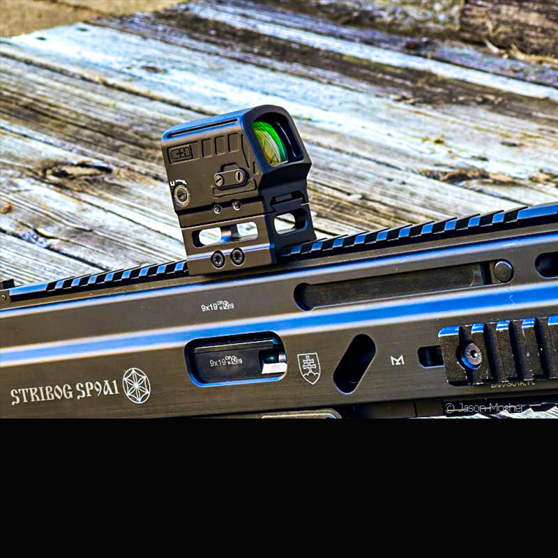 A view of the side of the Strykr optic, a square black optic, mounted on the rail of a short PDW firearm. 