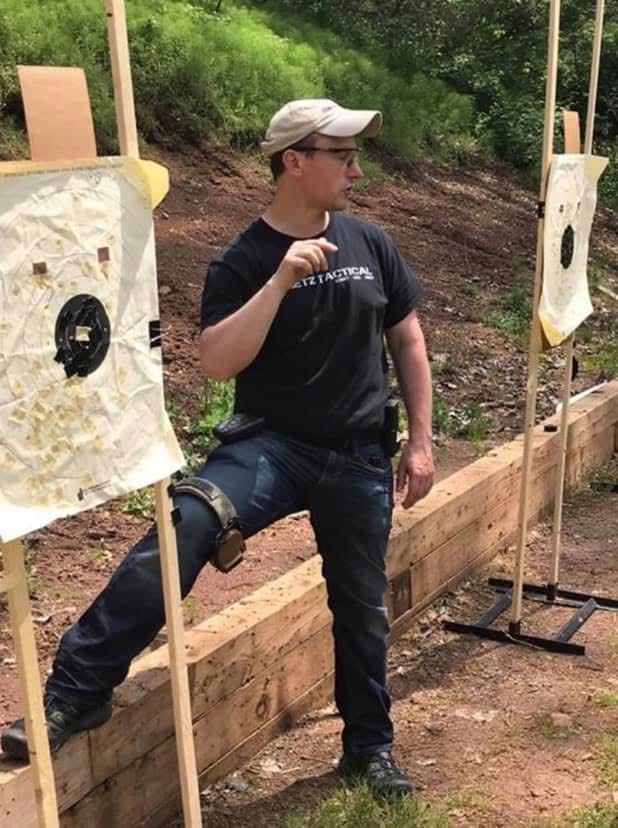 Firearms Instructor Ken Stretz Stands at a student's bullseye target and discusses handgun accuracy